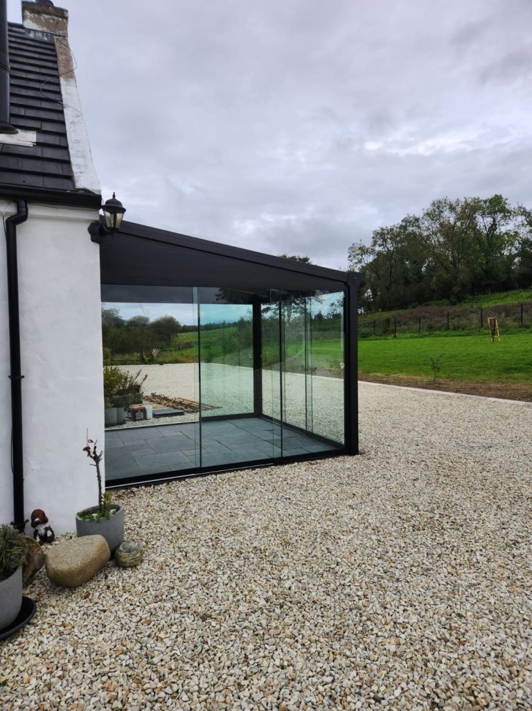 Pigato veranda with glass sides on a gravel patio