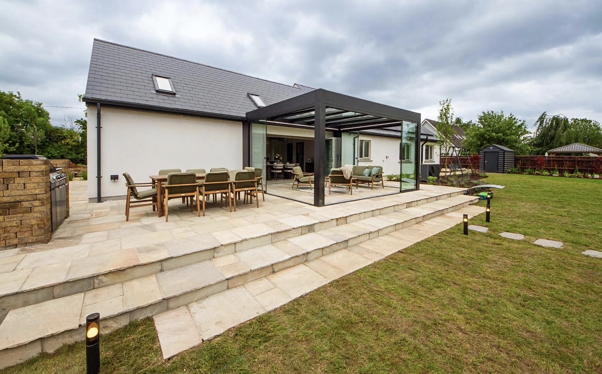 Wide view of the Apex Verandas glass pergola, dining area and garden from DIY SOS: The Big Build Ireland in Kildare