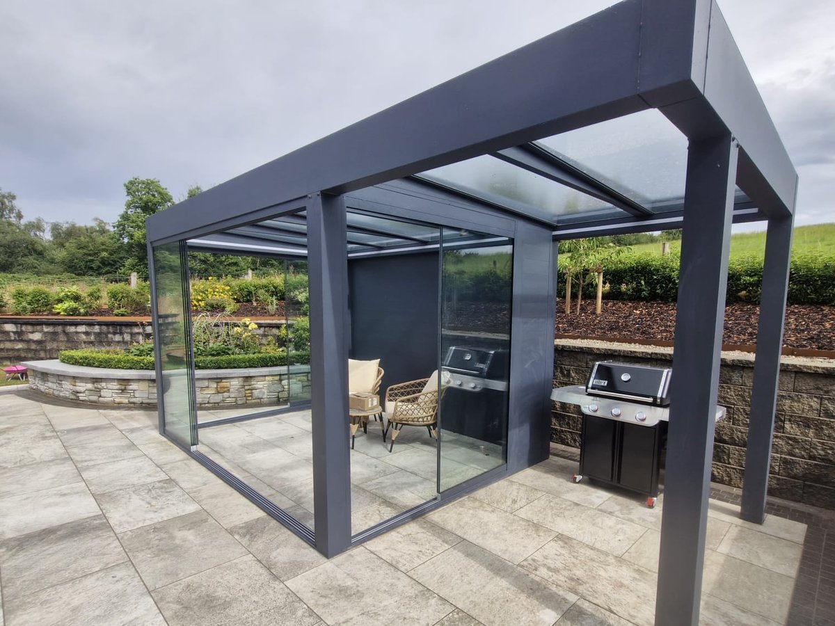 Freestanding grey glass pergola with glass sliding doors on a patio in Dublin