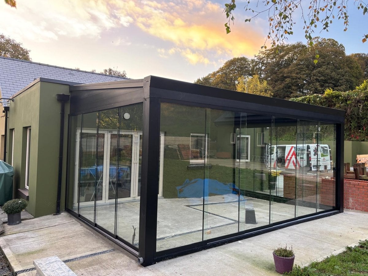 Black-framed glass room with frameless glass sliding doors on a bungalow in Co. Clare, at sunset