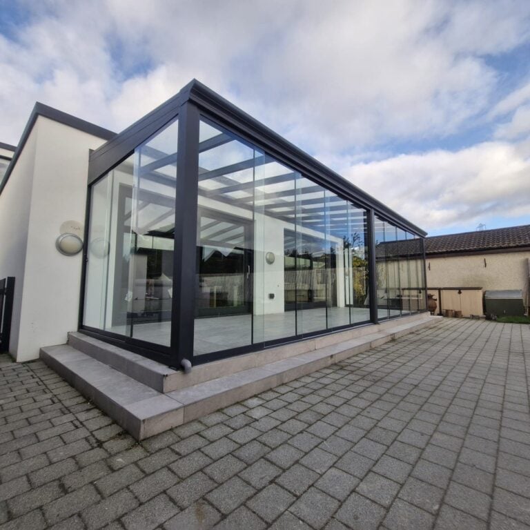 Glass room with frameless sliding doors on a raised patio