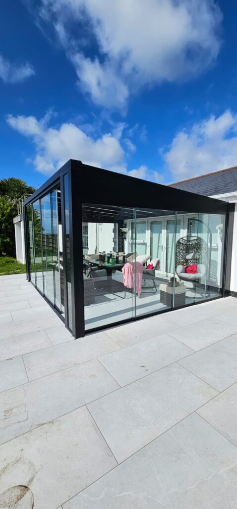 Pinela Glass room with a black frame and sliding glass doors on a paved patio